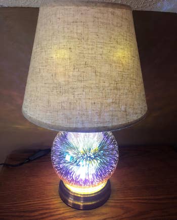 a reviewer photo of the same lamp turned on with the based featuring a dimensional light effect 
