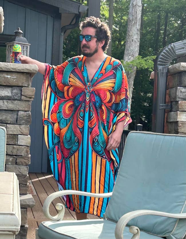 Person successful a vibrant, flowing kaftan with a butterfly signifier and striped design, lasting successful a patio setting