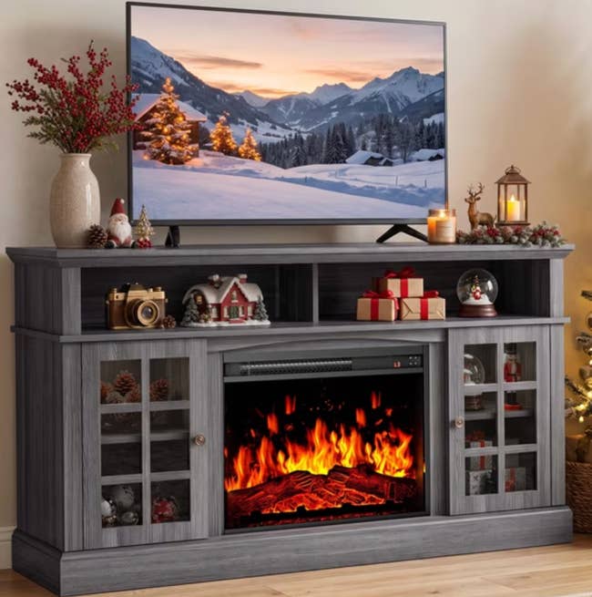 Entertainment halfway with a TV showing a snowy landscape, a faux fireplace below, and vacation décor similar candles and ornaments connected top