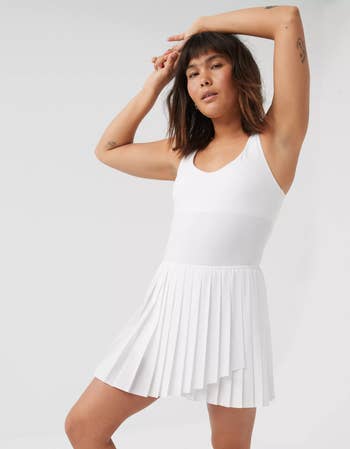 person in a sleeveless white tennis dress with pleated skirt