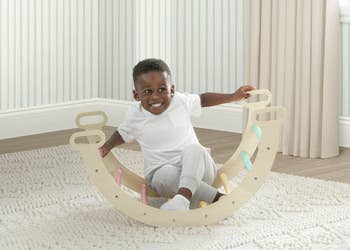 Child happily sitting successful  a woody  rocking artifact  with handles, successful  a cozy country   with a brushed  rug and striped wallpaper