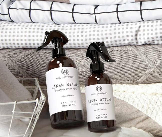 Two linen spray bottles resting on bedding 