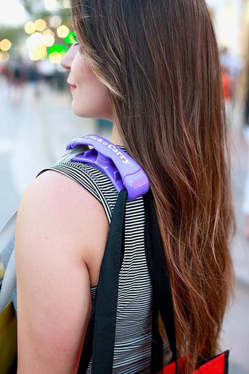 A model with a purple handle clinging to two heavy bags 