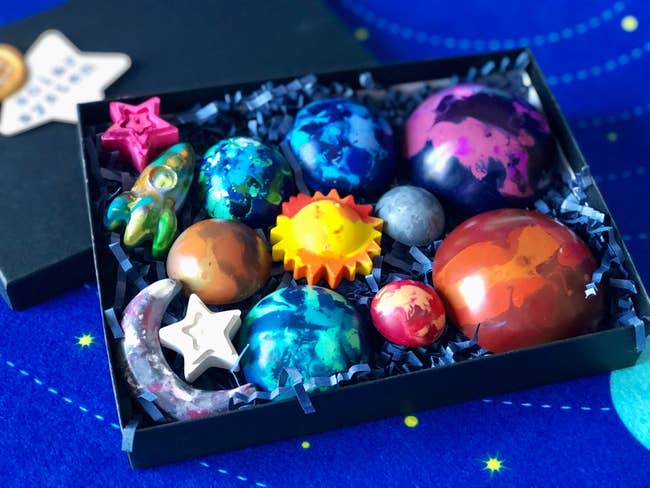 crayons shaped like planets, a rocket, stars, and the sun