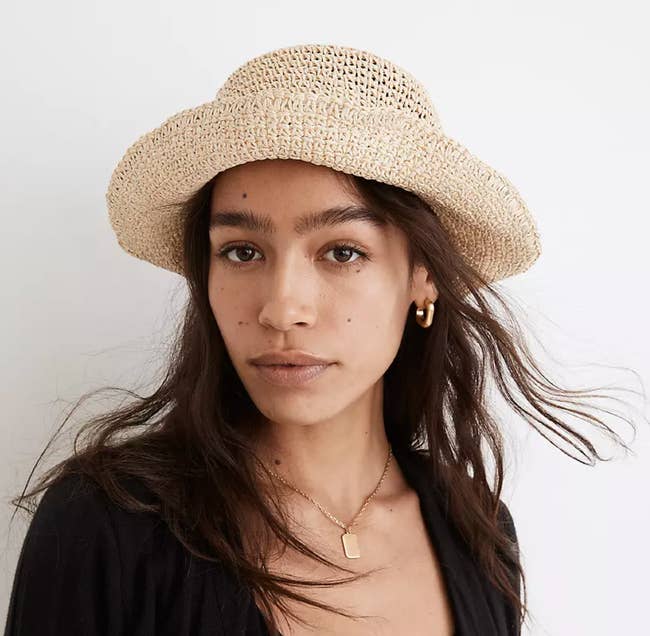 Model is wearing a straw bucket hat with the brim folded up