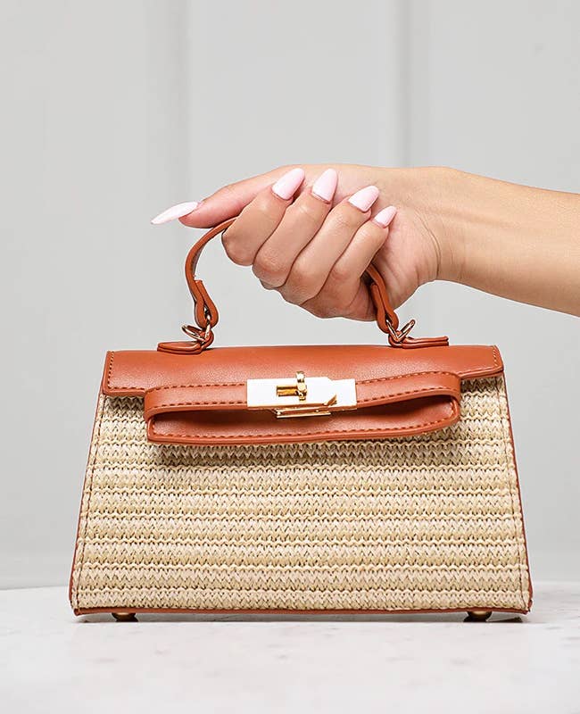 model holding the top handle of the neutral-colored bag