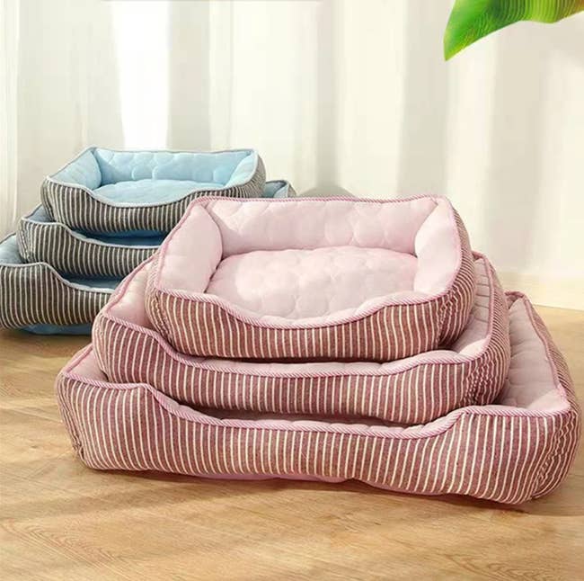 Pink and white striped dog beds in different sizes stacked on top of one another
