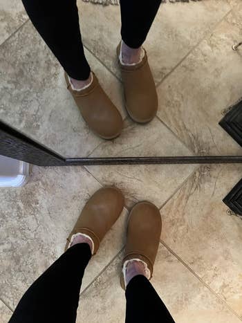 A idiosyncratic   wearing leggings and shearling-lined clogs is lasting  successful  beforehand   of a reflector  connected  tiled flooring