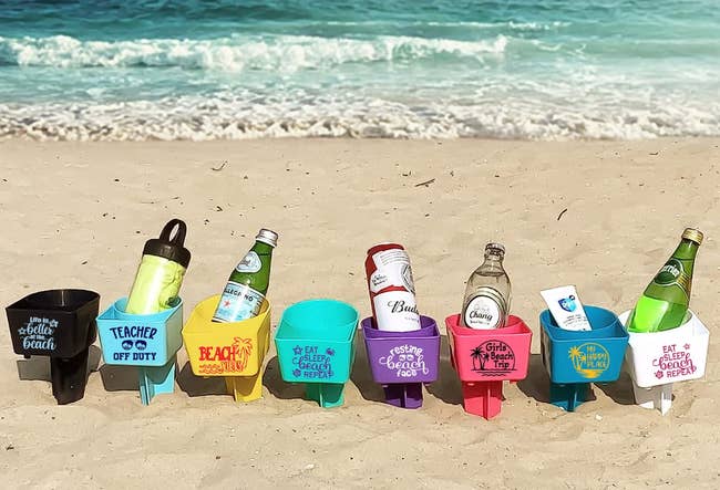Assorted beverage holders with amusive  quotes lined up   connected  a sandy beach