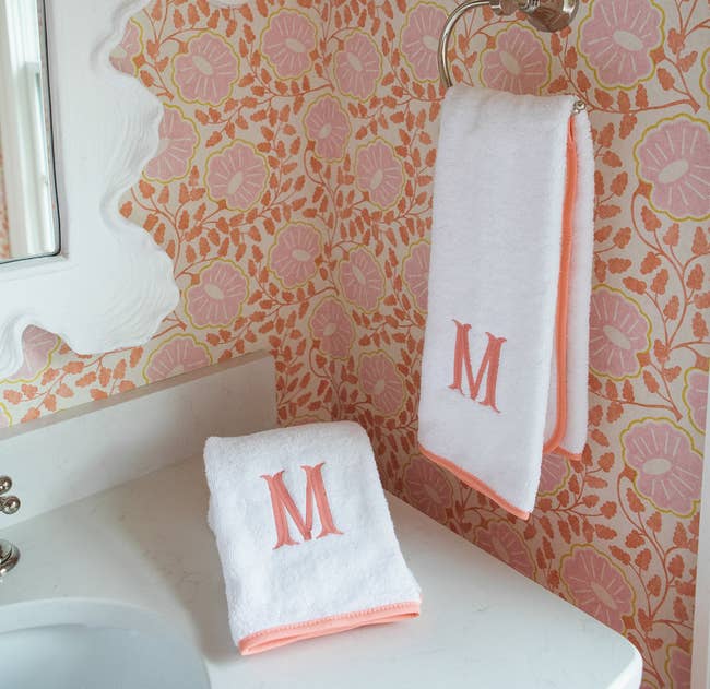 two hand towels with pink piped edges monogrammed with an 