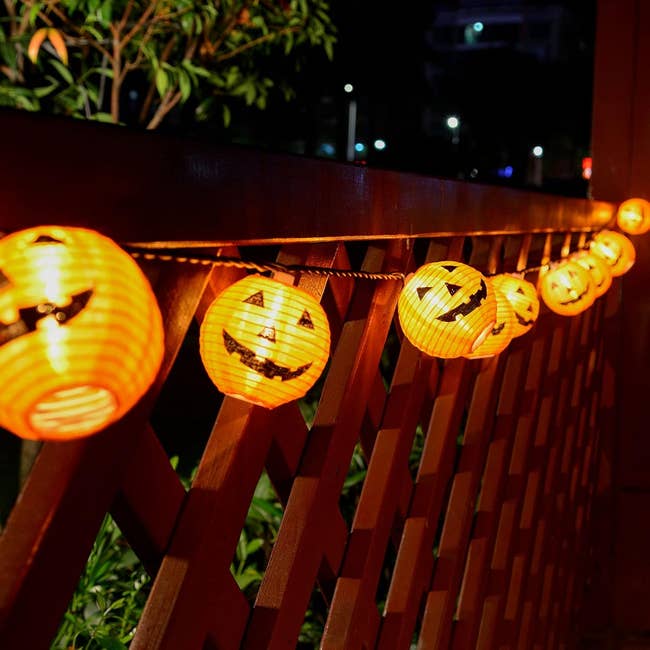 String of Jack-o'-lantern Halloween lights hanging on a woody obstruction astatine night, creating a festive and spooky ambiance