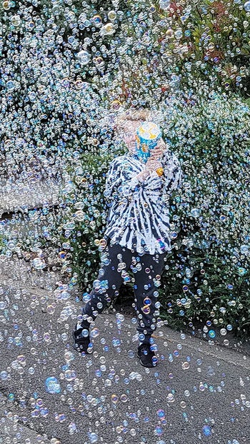 A child hidden behind thousands of bubbles made by the bubble machine