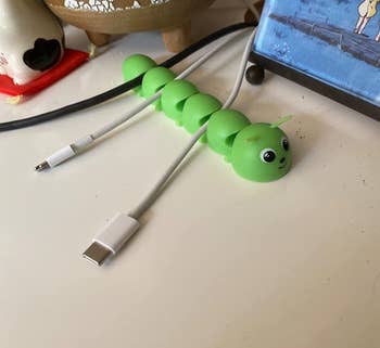 Reviewer's caterpillar cord organizer on their desk holding their cables securely