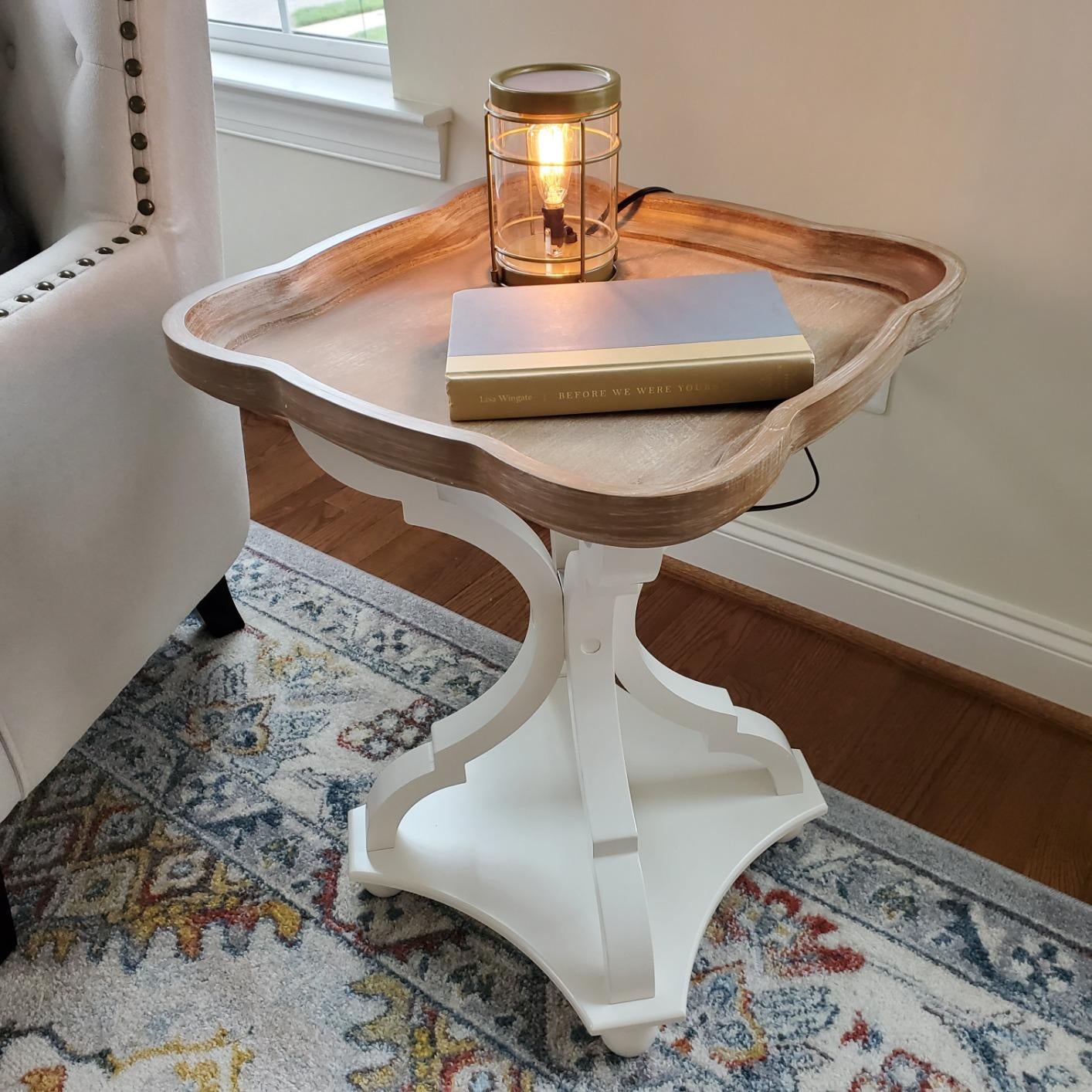 reviewer photo of the white and wood table holding a book and lamp