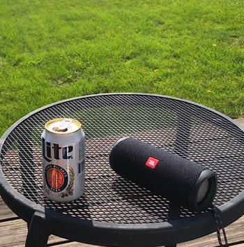 reviewer photo of the black speaker on an outdoor table next to a can of beer
