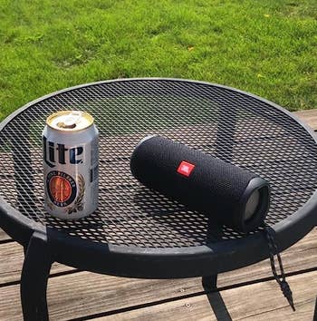 reviewer photo of the black speaker on an outdoor table next to a can of beer