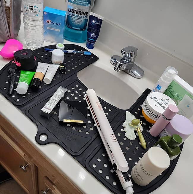 A variety of skincare products and tools arranged on reviewer's black sink-top organizer