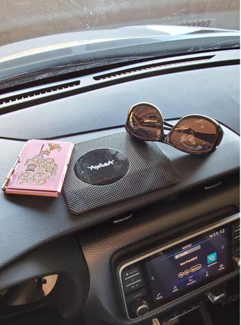 another reviewer photo of the black mat on a dashboard with a phone and sunglasses on it