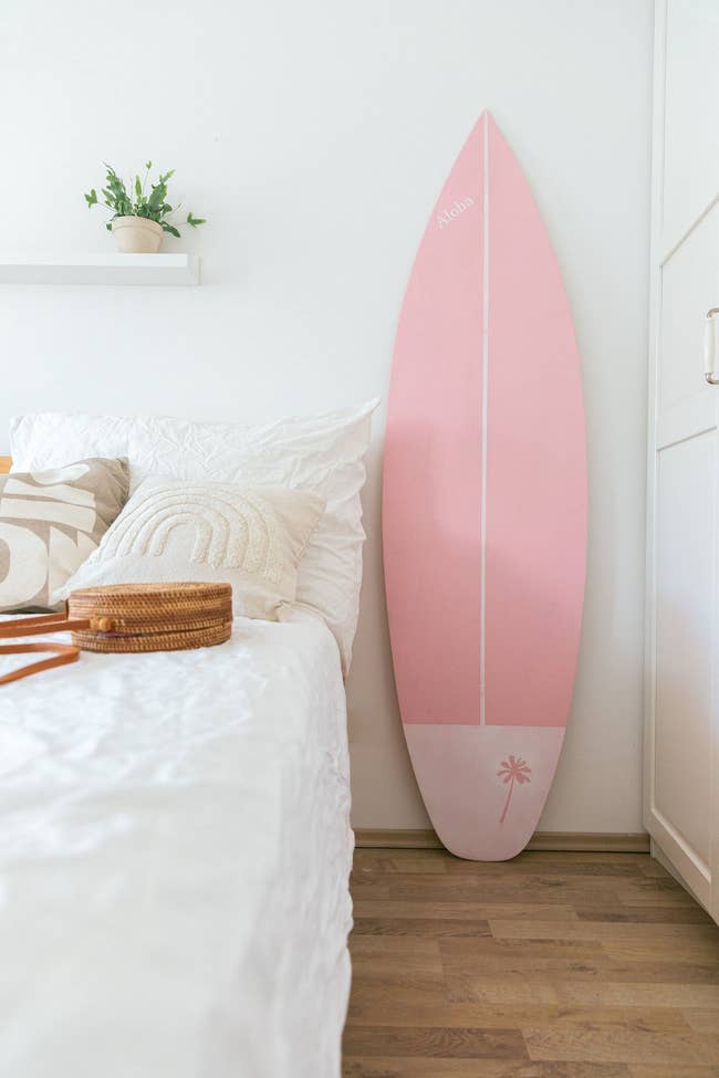 The surfboard next to a white bed