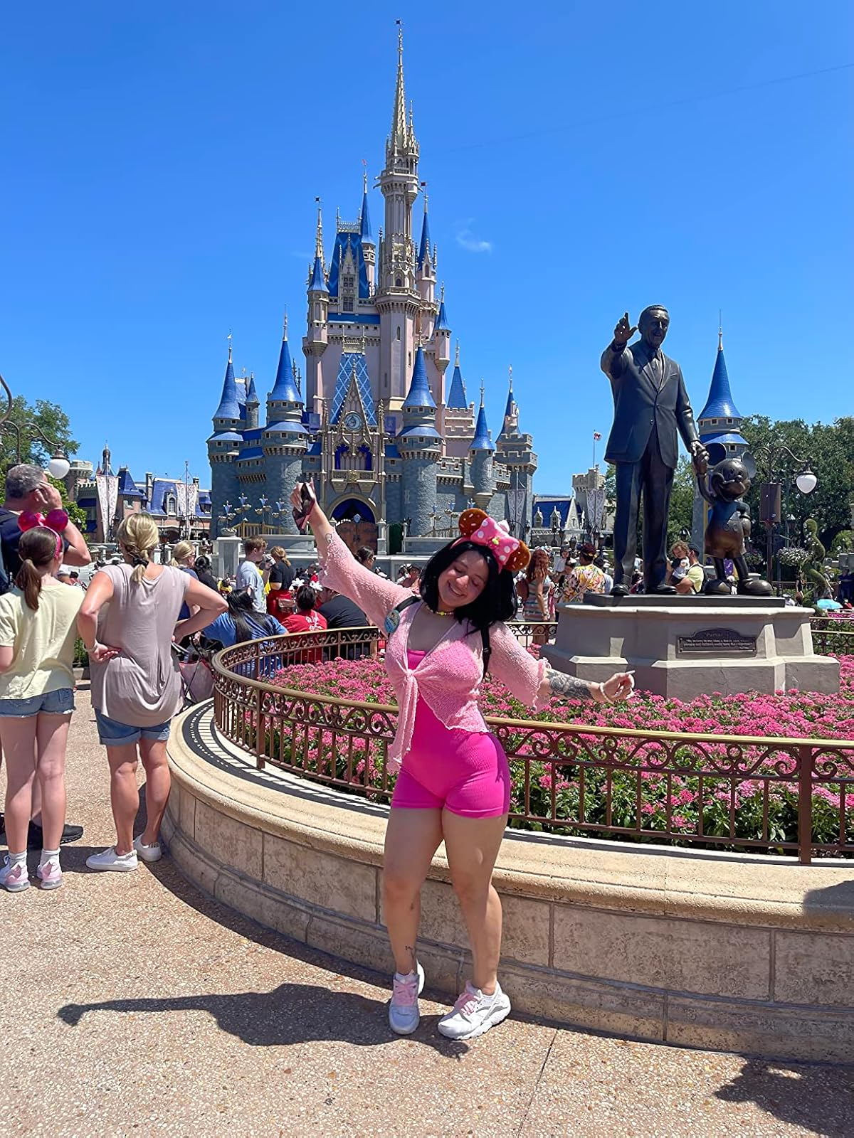 Person posing happily successful  beforehand   of a fairy-tale castle, wearing taxable   park-inspired attire with Mickey Mouse ears and pinkish  shorts