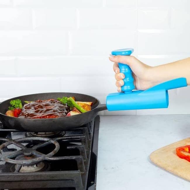 Model holding onto blue attachment grip on a pan handle that supports their elbow while letting them grab it vertically with their fist 