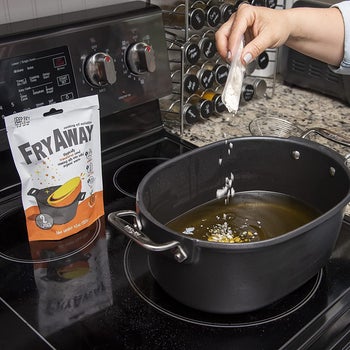 a hand sprinkling white flakes into a pan of oil