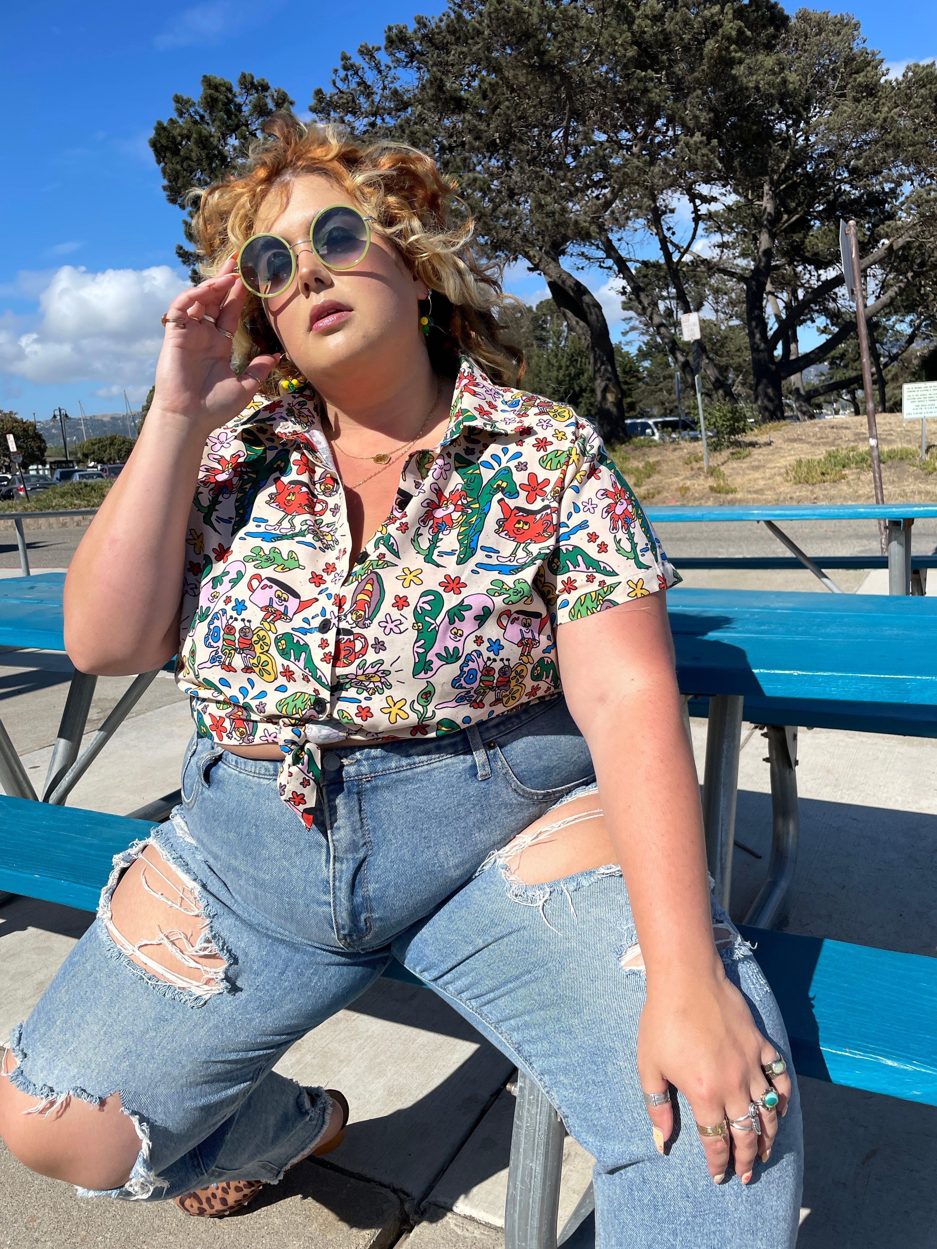 a model wearing the shirt that is white with bugs and leaves and other illustrated characters on it