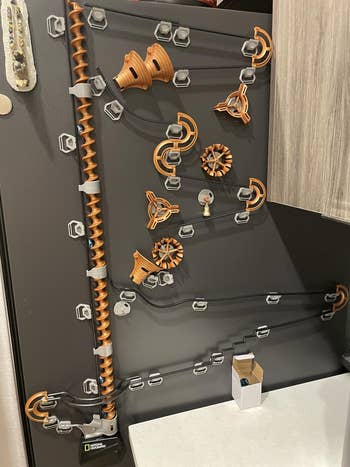 Wall-mounted marble maze featuring intricate tracks and gears, showcasing a creative kitchen organization or decor concept