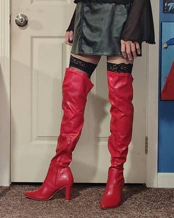 Person wearing thigh-high reddish  boots with a abbreviated  leather skirt and patterned stockings, lasting  indoors