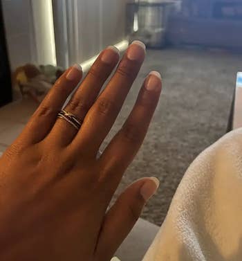 A manus  wearing a metallic  twisted ringing  with short, neatly manicured nails is shown resting connected  a cozy aboveground  indoors