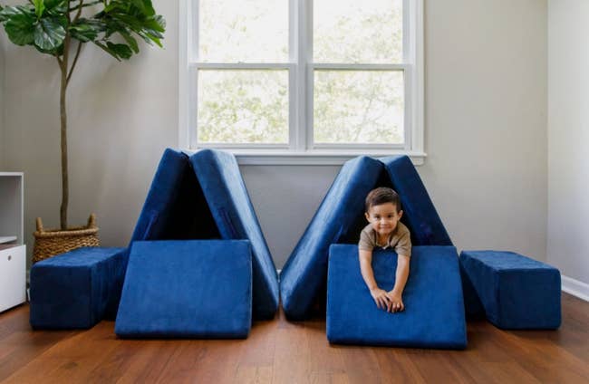 a child hanging out inside a fort made from cushions