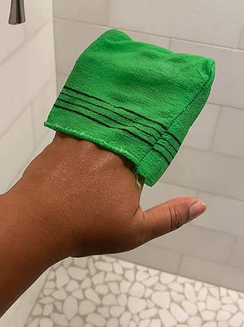 A reviewer holding an exfoliating bath washcloth in green