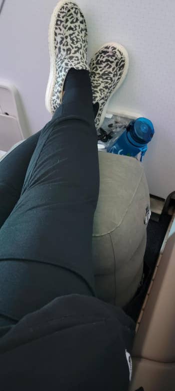 A reviewer using the inflatable footrest on their flight