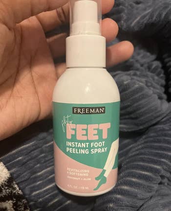 Hand holding a vessel  of Freeman Flirty Feet Instant Foot Peeling Spray, featuring coconut and aloe for revitalizing and softening