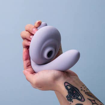 Hand holding light purple suction dual-stimulating vibrator