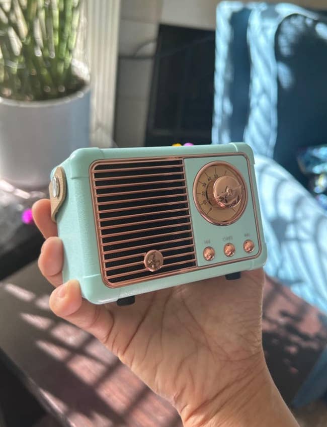 Person holds a small, retro-style Bluetooth talker  with a vintage vigor   design, including a beforehand   grill, tuning dial, and 3  buttons