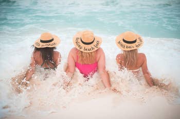 Reviewer pic of three people laying in the beach with hats that say hello sunshine, resting beach face, and beach hair don't care