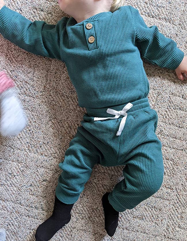 a reviewer photo of a baby wearing the outfit in a deep green