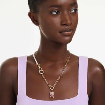 Person wearing a sleeveless apical  and a mixed concatenation  necklace with a teddy carnivore  pendant, suitable for a manner  buying  article