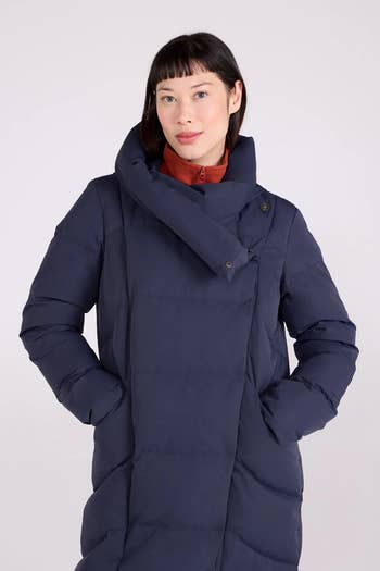 Person wearing a stylish puffer overgarment  with an asymmetrical collar, suitable for acold  weather, implicit    a high-neck top