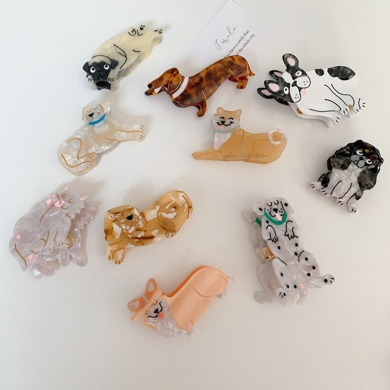 hair claws shaped like a pug, lab, corgi, cocker spaniel, dalmatian, king charles, dachshund, frenchie, shiba inu, and one shaped like a cat.