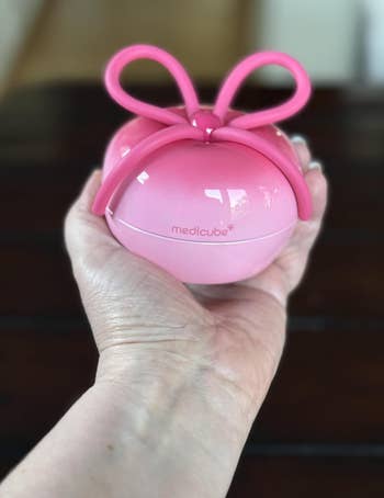 Hand holding a circular  pinkish  quality   instrumentality  with 