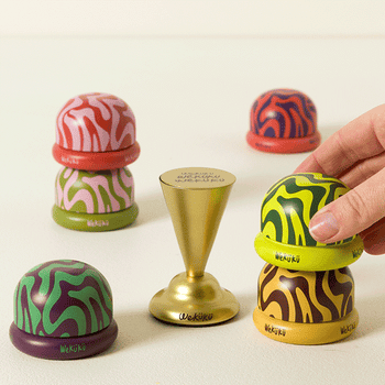 Hand stacking colorful, patterned artifact  Wekikū pods with a golden  balancing instrumentality   successful  center; playful and vibrant. Ideal for interactive play   oregon  decor
