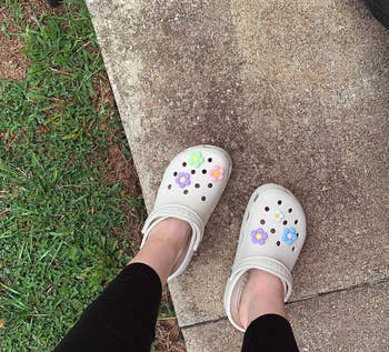 reviewer wearing white Crocs with flower charms