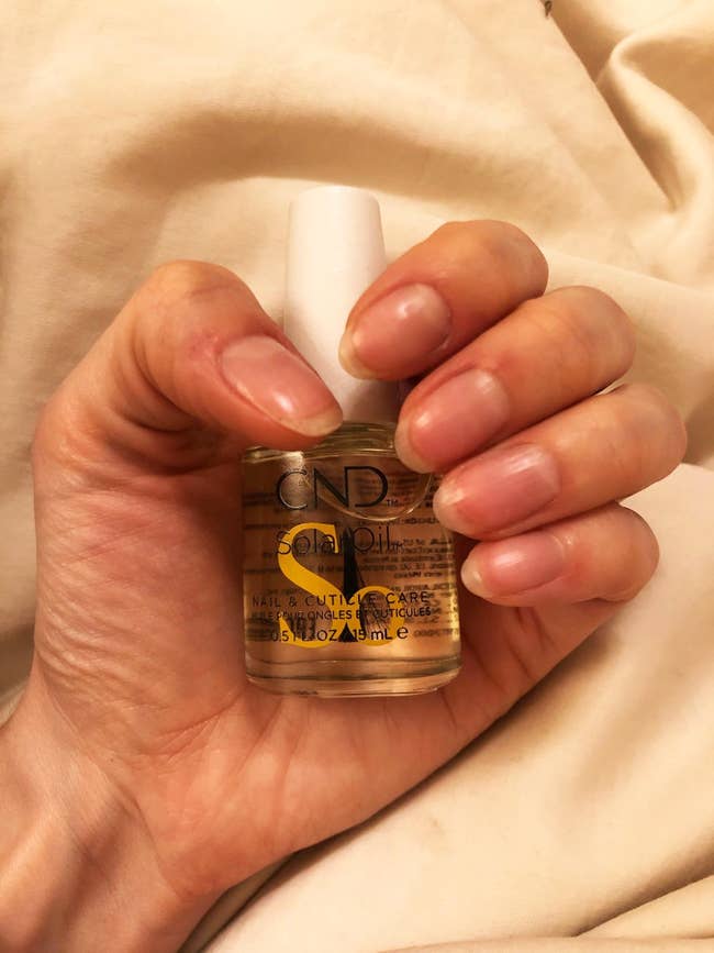 reviewer holding a bottle of nail oil