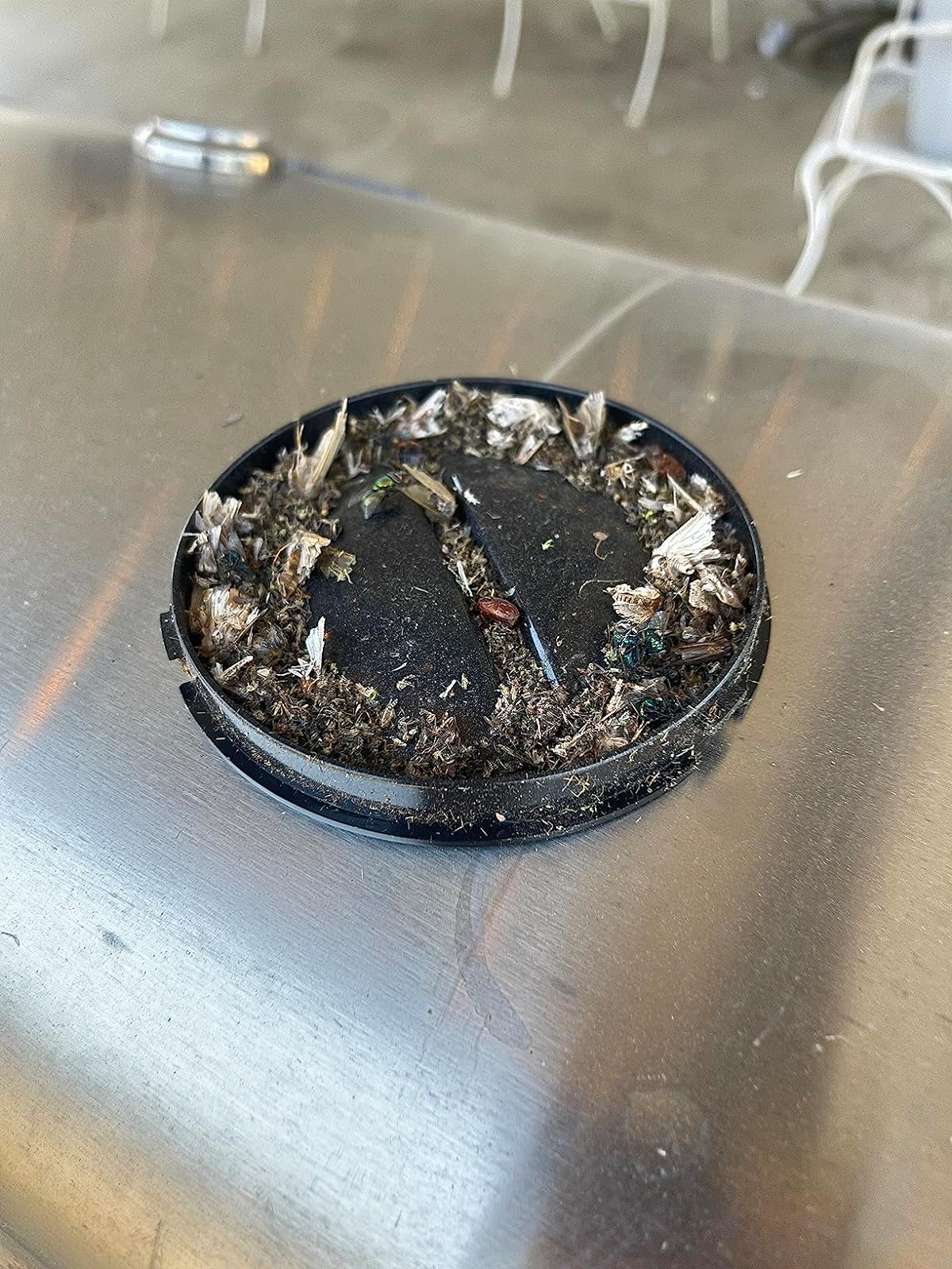 Ashtray filled with cigarette butts on a metal surface