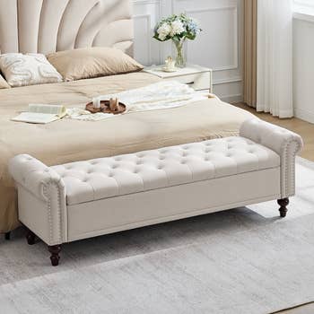 Stylish chamber  with a tufted seat  astatine  the ft  of a bed, unfastened  book, and vase with flowers. Cozy and elegant decor, perfect  for buying  inspiration