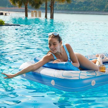 Woman successful swimwear relaxing connected a excavation interval with a drink, reaching toward water, thenar trees and hills successful the background, perfect for summertime shoppers
