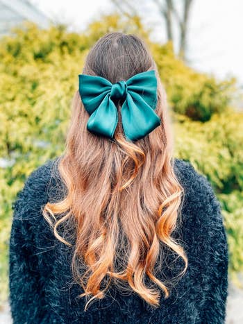 reviewer wearing large green bow in back of their hair