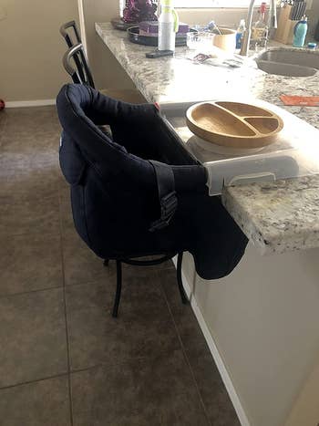 reviewer's photo of the high chair clamped onto a kitchen counter